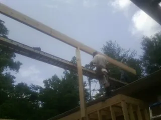 Carpenter setting a ridge beam over a new addition frame — Ice Dam Removal by Roofing Brothers in Aultman