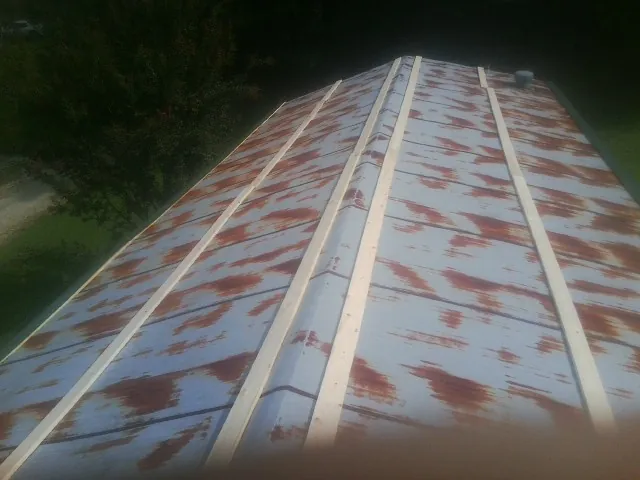 Rusted metal roof panels with new wood purlins before replacement — Storm Damage Roof Repair in Aultman by Roofing Brothers