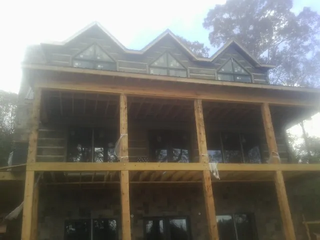 Dormers and porch framing on a large log home under construction — Roof Coating work by our crew in Aultman