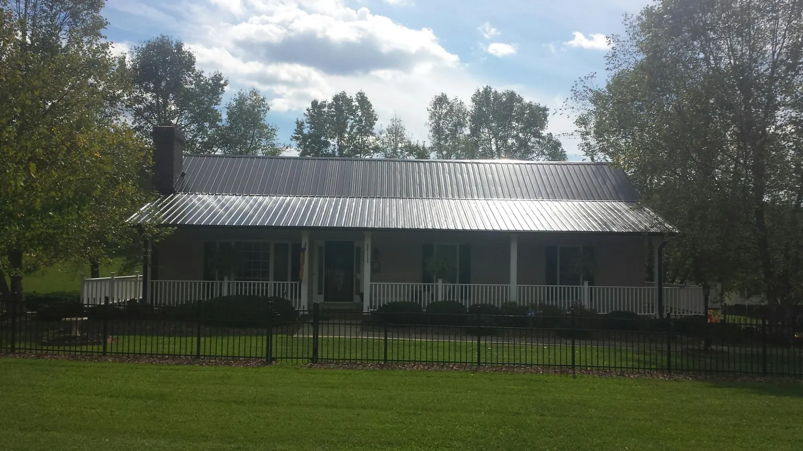 Gray metal roof on a brick ranch with a full width front porch — Gutter Guard Installation work by our crew in Aultman