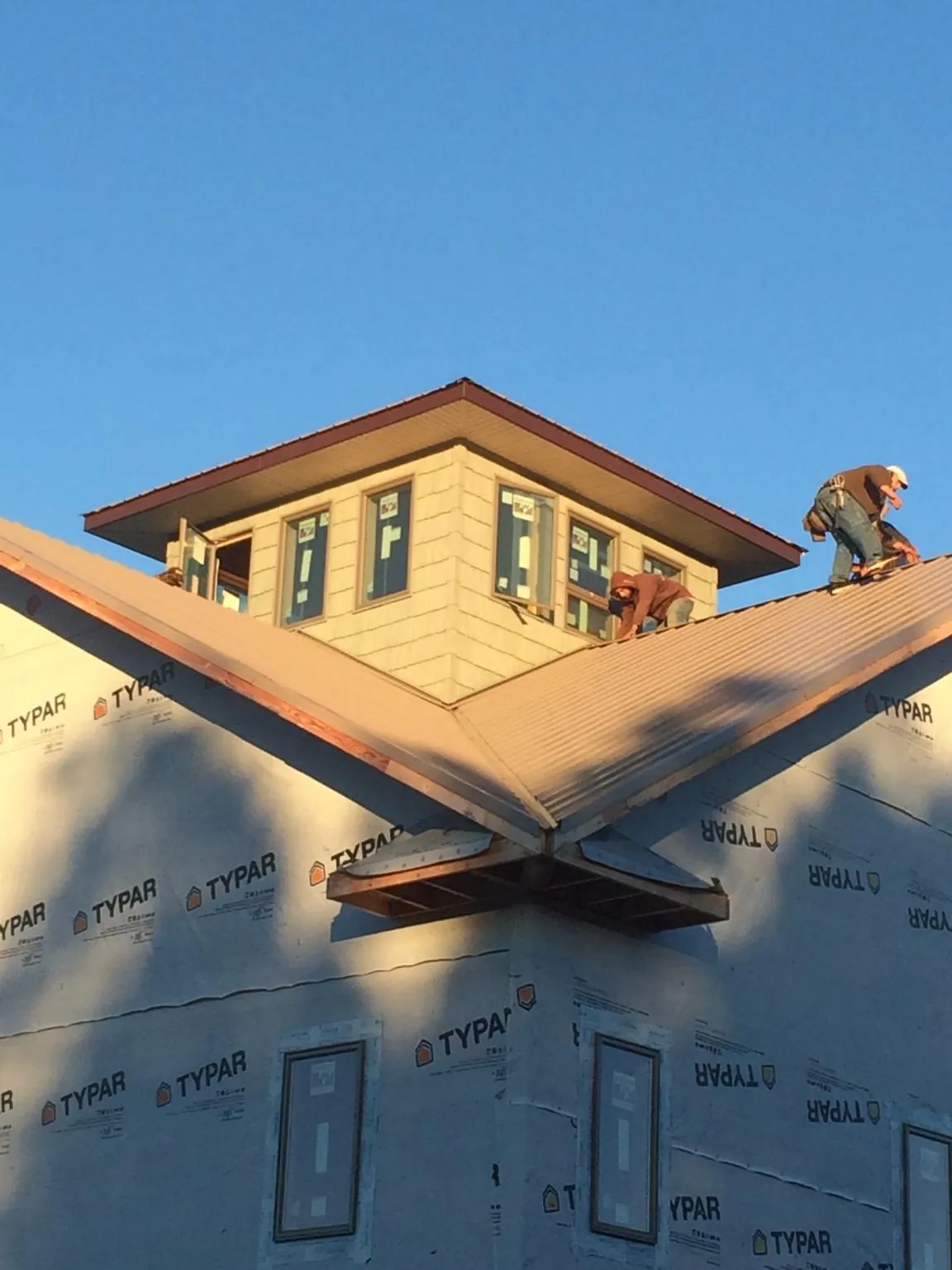 Roofers working around a rooftop cupola on a new metal roof at sunset — Roof Waterproofing in Aultman by Roofing Brothers